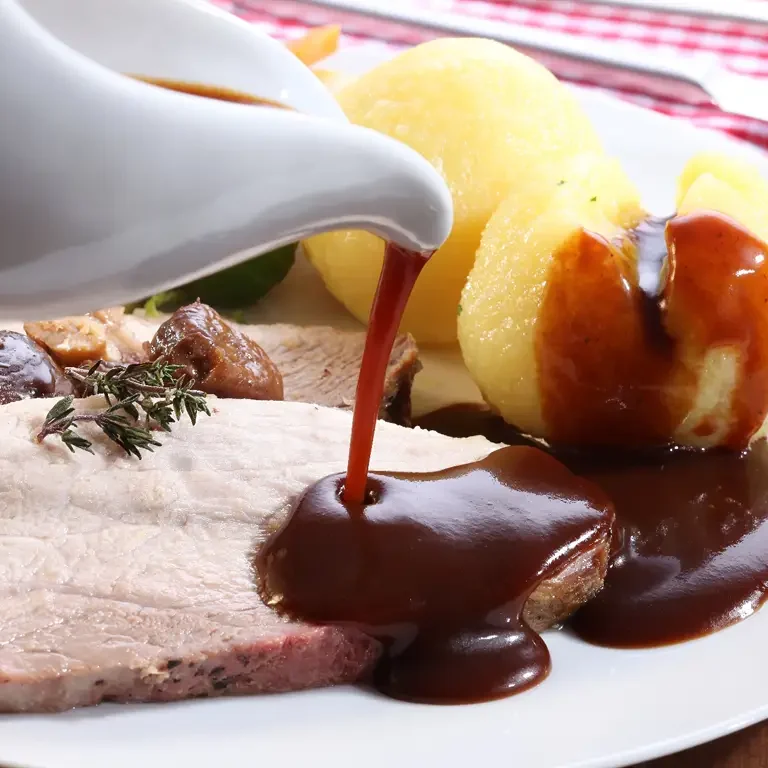 Traditioneller Schweinebraten mit Klößen, übergossen mit Bratensauce