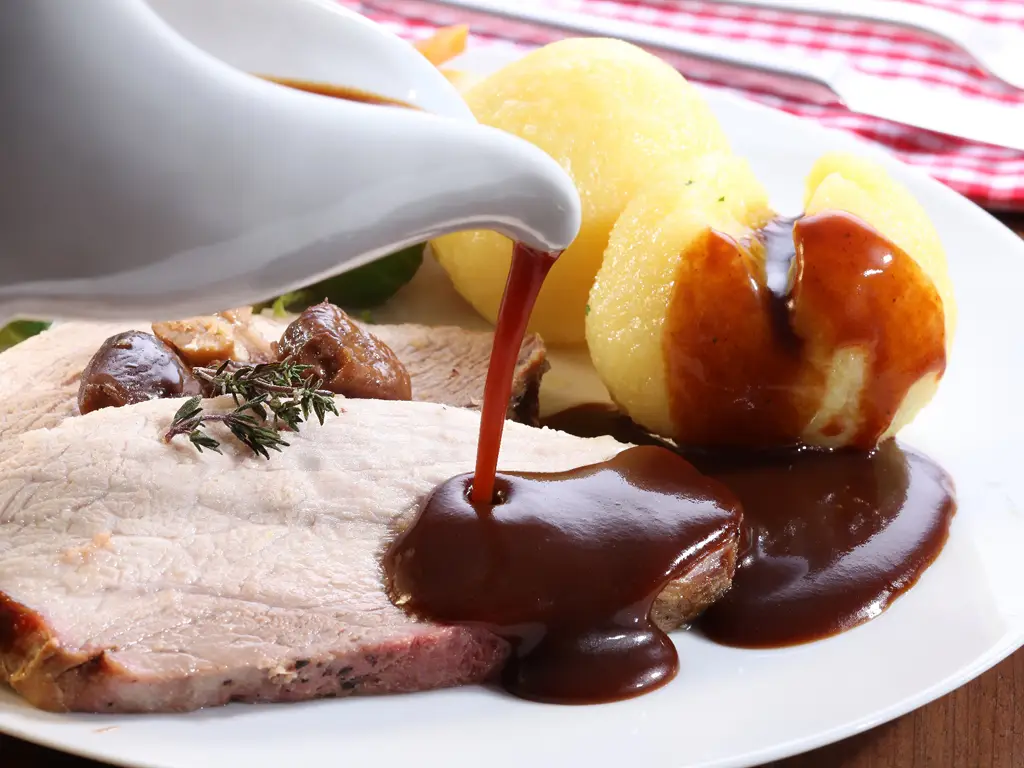 Traditioneller Schweinebraten mit Klößen, übergossen mit Bratensauce