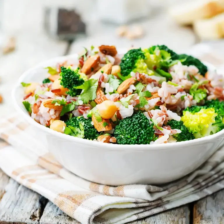 Eine Schale mit frischem Brokkoli-Reis-Salat, garniert mit Mandeln und frischen Kräutern.