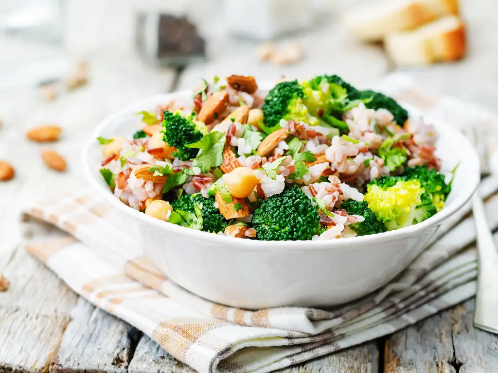 Eine Schale mit frischem Brokkoli-Reis-Salat, garniert mit Mandeln und frischen Kräutern.